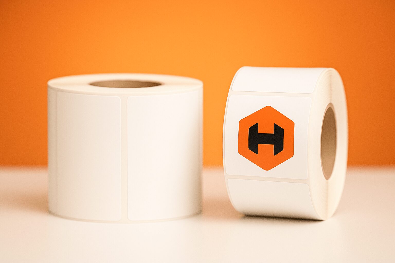 Two label rolls side by side, one blank and one with the Hickman logo printed on them